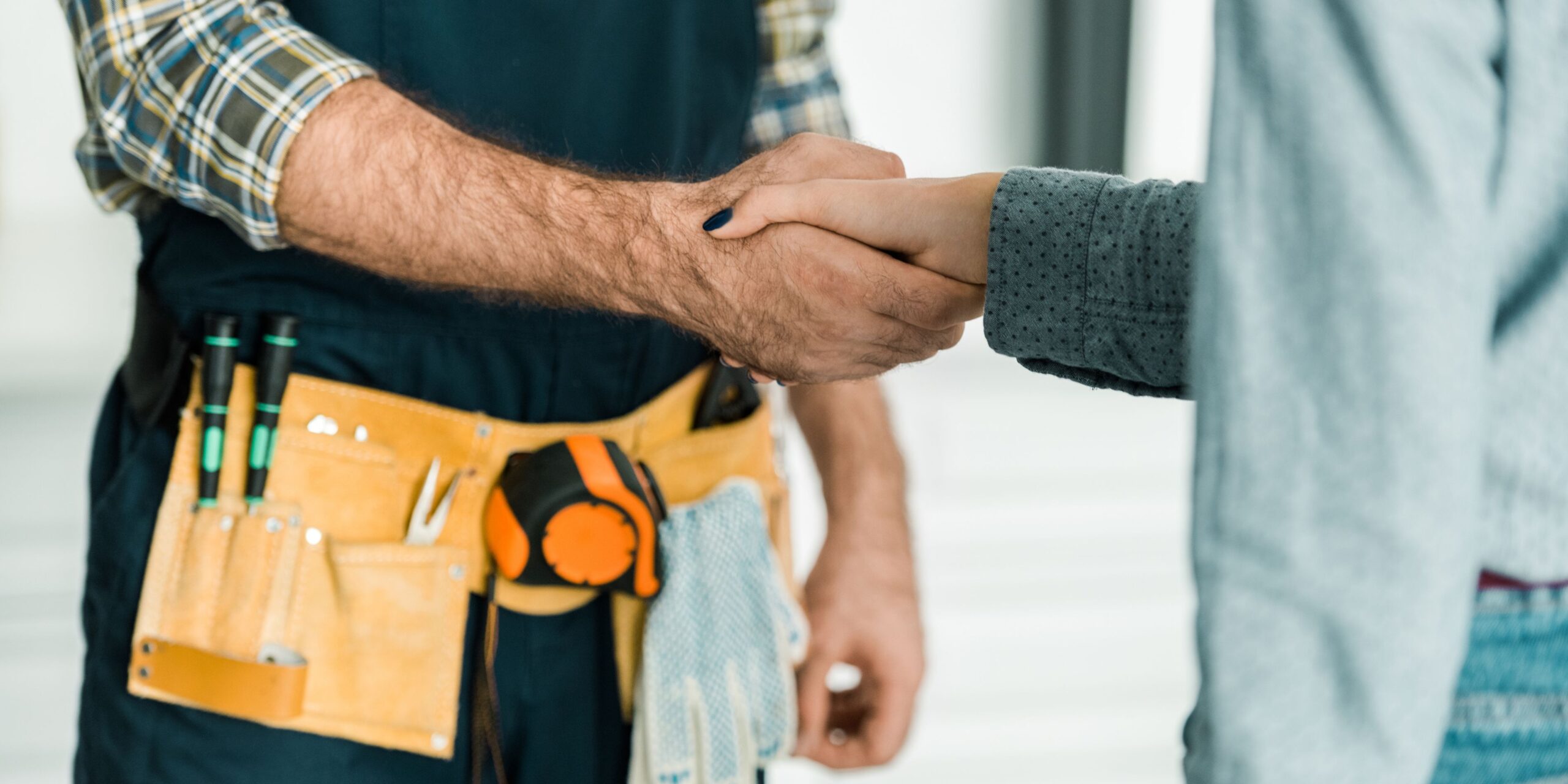 FPS Plumbing Blog Graphics (1) Plumber wearing a tool belt shaking hands with a customer